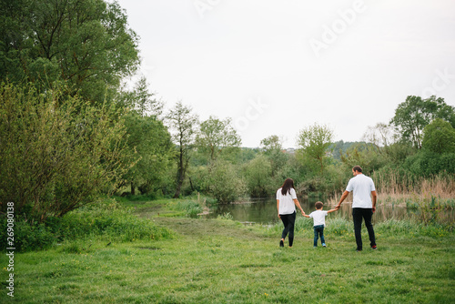 Happy family: mother father and child son on nature on sunset. Mom, Dad and kid laughing and hugging, enjoying nature outside. Sunny day, good mood. concept of a happy family © Serhii