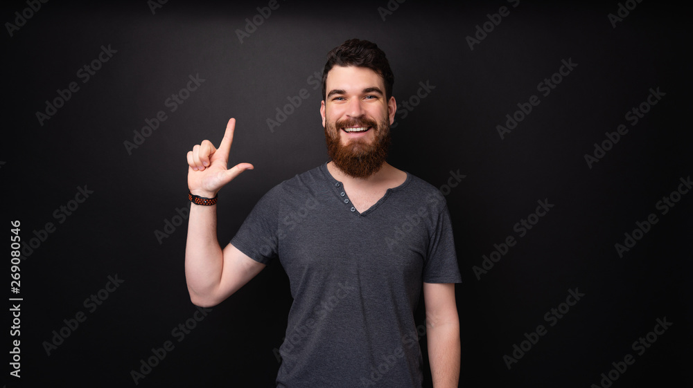 Photo of a bearded man pointing up and loooking at camera over dark background Photo of a bearded man pointing up and loooking at camera over dark background