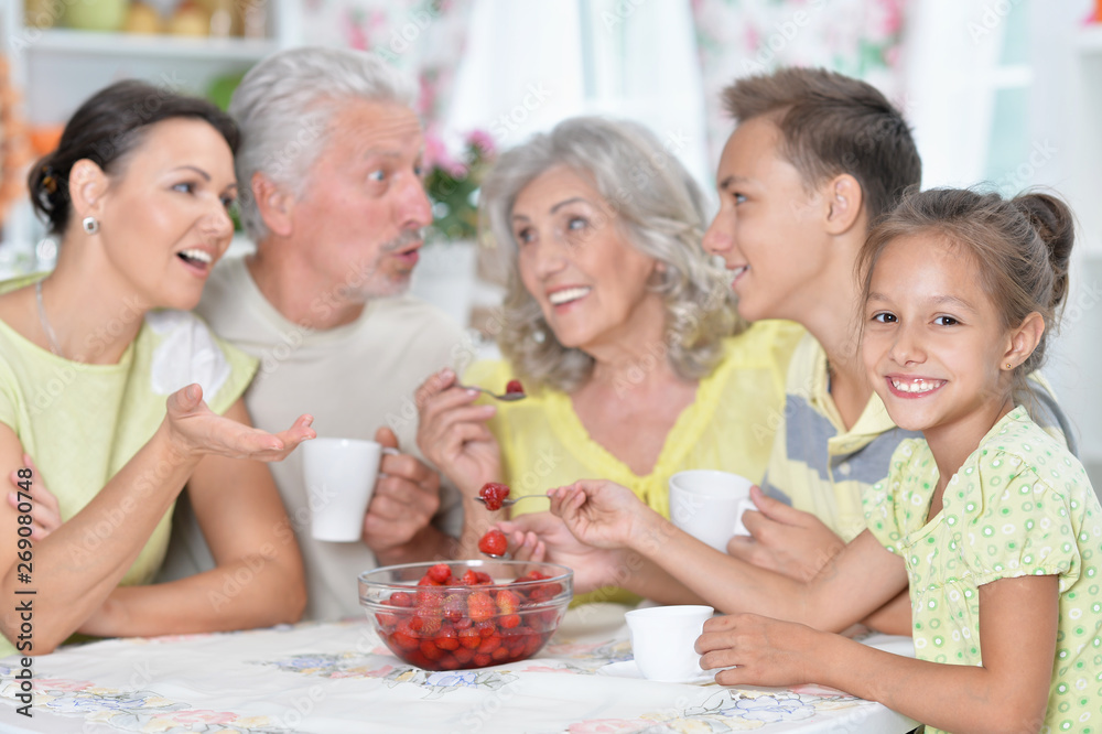 Portrait of big happy family eating fresh strawberries at kitchen