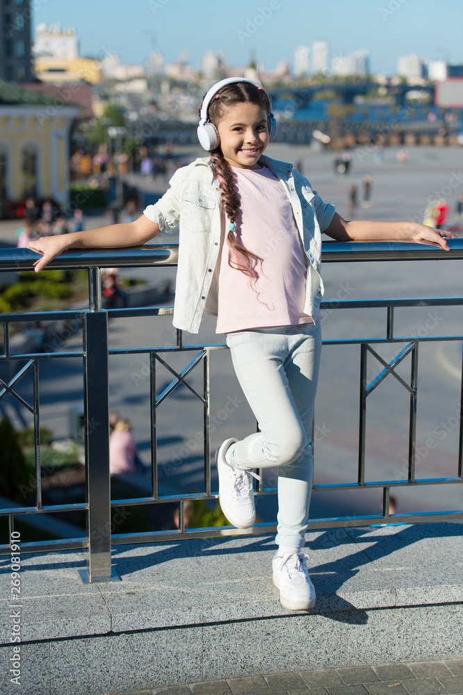 Obraz premium Exciting journeys through cities and museums. City guide and audio tour. Girl little tourist kid using audio guide mobile application. Audio tour headphones gadget. Free style of travelling