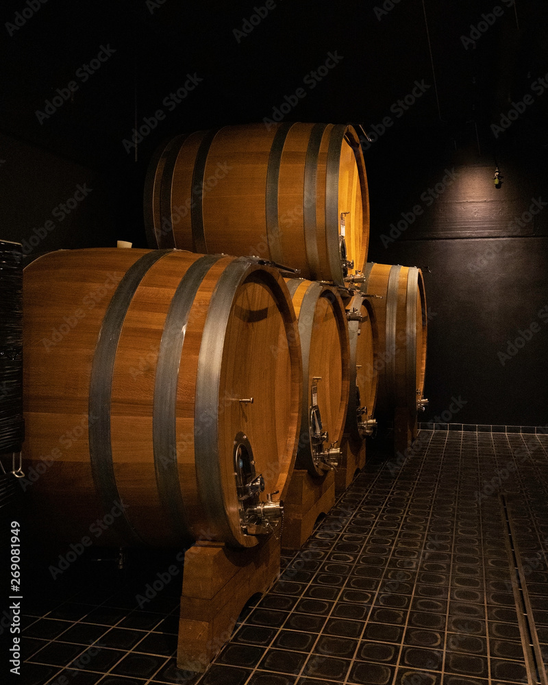 Row of big wooden oak barrels in wine cellar. Winemaking and wine tasting concept.- Image