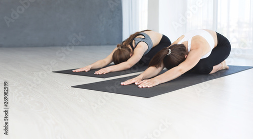 Two sporty girls laying in Child position after hard yoga class