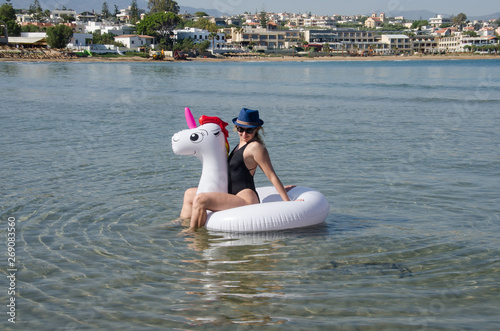 Woman relaxing on inflatable unicorn float near sea with Chania Crete background