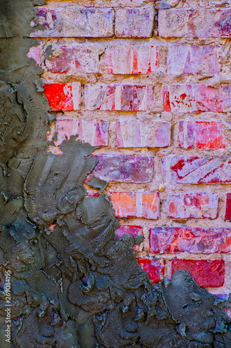 Old red brick wall half covered with cement plaster