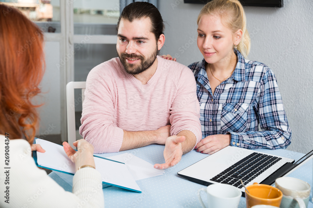 Obraz premium Young family and mother with documents sitting at table in home interior