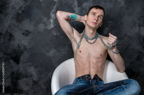 Canvas Print Handsome skinny guy holding a chain. Black background