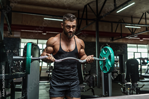 Young handsome sportsman bodybuilder weightlifter with an ideal body, after coaching poses in front of the camera, abdominal muscles, biceps triceps. In sportswear. photo