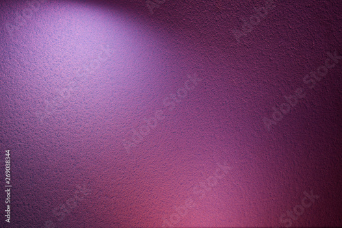 On a purple textural background, a light violet ray of light and a pink spot of light