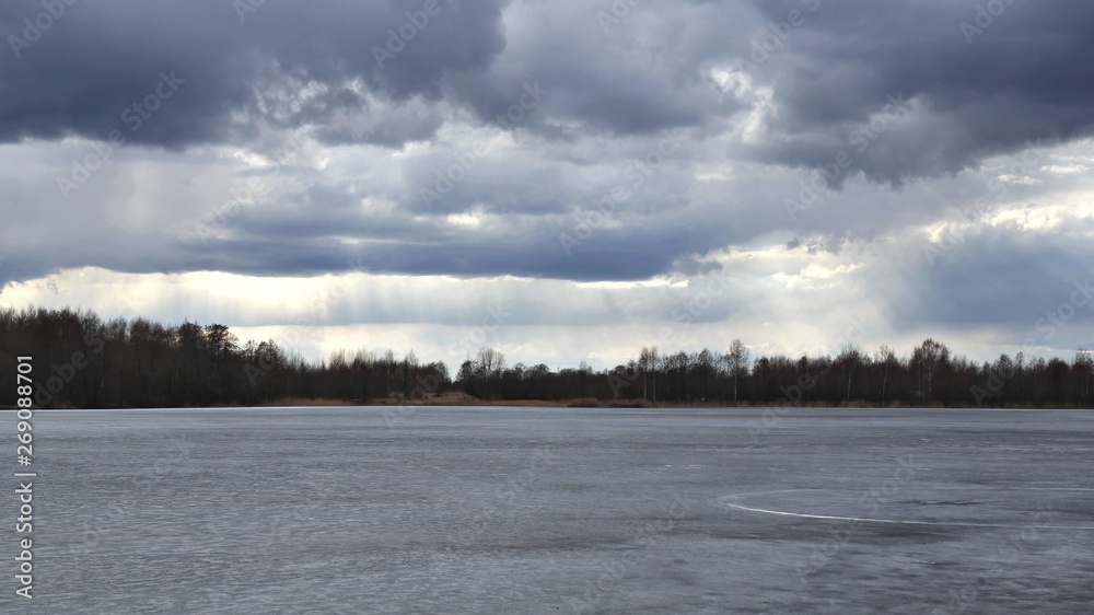 Frozen lake, forest, clouds and suns rays Frozen lake, forest, clouds and suns rays