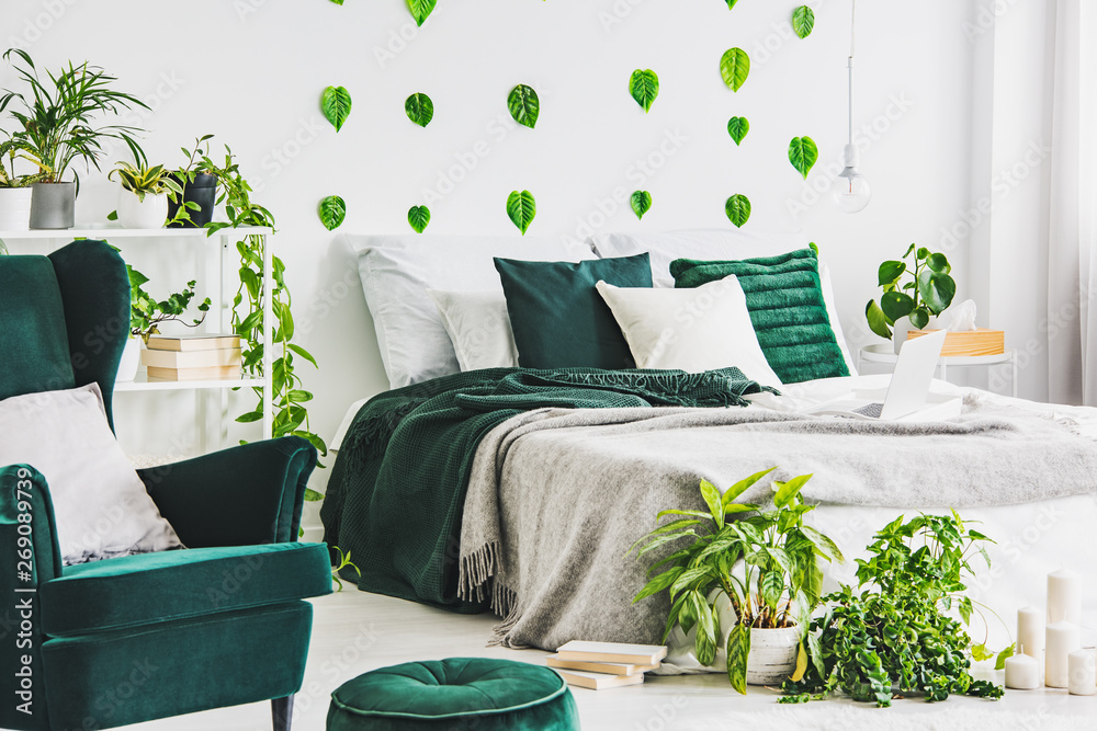 White bedroom interior with king size bed with grey nd emerald bedding,  urban jungle and green leaf on the wall foto de Stock | Adobe Stock