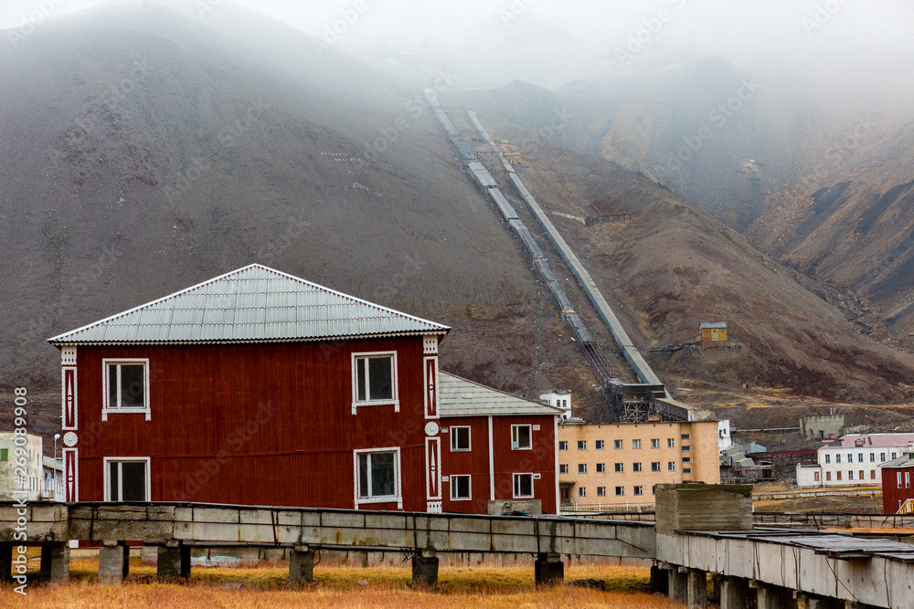 The sudden abandoned russian mining town Pyramiden, old red house with old coal mine in the back, Isfjorden, Longyearbyen, Svalbard, Norway.
