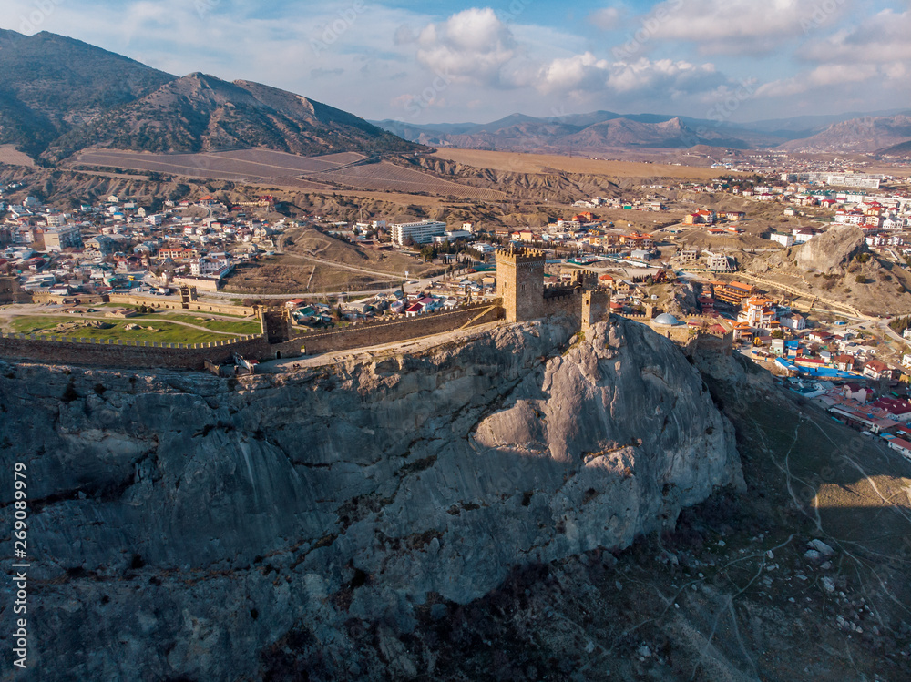 Genoese fortress in Sudak, Crimea. Aerial panorama view of ruins of ancient historic castle or fortress on crest of mountain near sea