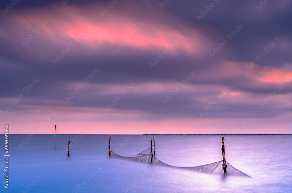 Fishing nets in a large lake during twilight with sunset colored sky clouds