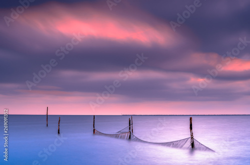 Fototapeta Naklejka Na Ścianę i Meble -  Fishing nets in a large lake during twilight with sunset colored sky clouds