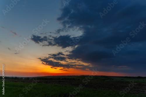 The sky with bright clouds lit by the sun after sunset over the field. © olgapkurguzova