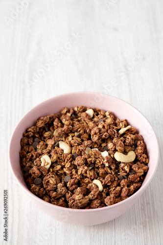 Homemade chocolate granola with nuts in a pink bowl, low angle view. Copy space.