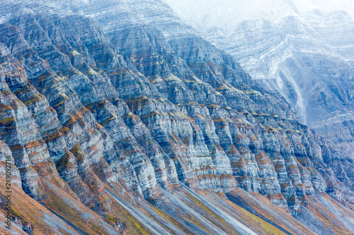 Billon year old jagged rock formations with different green moss and snow within, Svalbard, Isfjorden, Norway