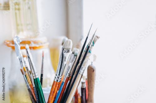 many different and dirty instruments of the artist (brushes, ankles, knives for palette, pencils) are in the jar on the window. Copy space
