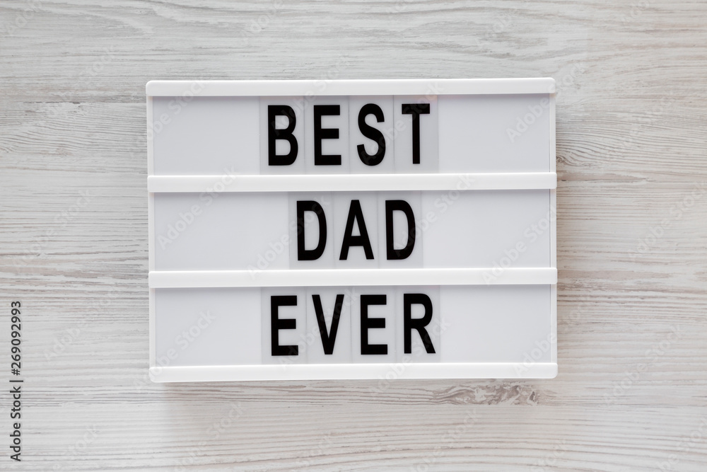 'Best dad ever' words on a lightbox over white wooden surface, top view. Overhead, from above, flat lay.