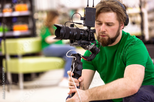 Videographer shooting a film or a television program in a studio with a professional camera, backstage