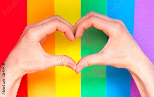 Hands show gesture of heart on rainbow lgbt background