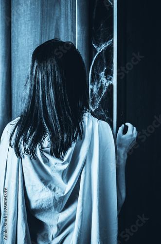 Young woman opens doors of a wardrobe with something creepy inside
