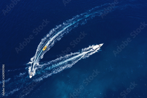 Yachts at the sea surface. Aerial view of luxury floating boat on transparent turquoise water at sunny day. Top view from drone. Seascape with motorboat in bay. Travel - image
