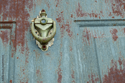 The paint has long ago peeled away and the door knocker on this exterior door shows the signs of rust and grunge.
