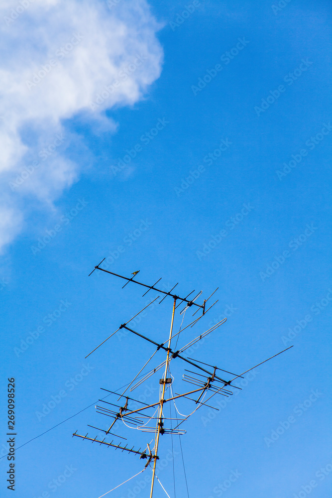 TV Televisions antennas with natural blue sky with puffy white clouds in bright clear sunny day TV Televisions antennas with natural blue sky with puffy white clouds in bright clear sunny day