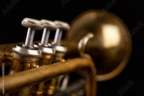 Old trumpet on a dark wooden table. Wind instrument in the old style.