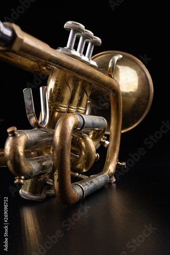 Old trumpet on a dark wooden table. Wind instrument in the old style.