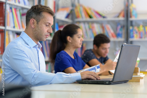 man in library using laptop for research