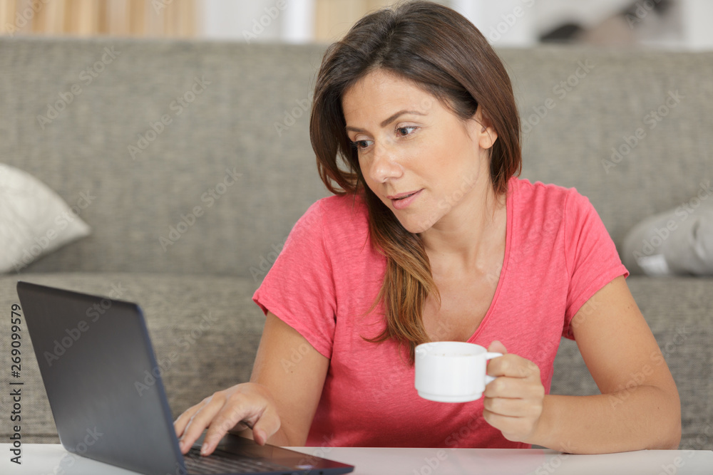 woman using laptop while drinking coffee woman using laptop while drinking coffee
