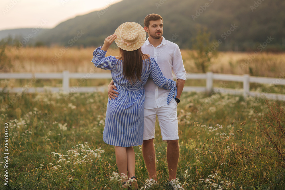 Women in blue dress and knitted had stand with man in white shirt. Couple in love