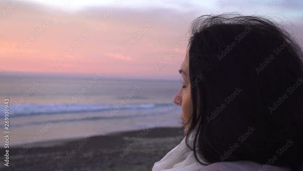 Close up side view face of mature woman looking at the ocean during sunset Close up side view face of mature woman looking at the ocean during sunset