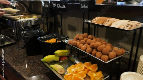 Going Down Breakfast Buffet Line Focusing On Food. The camera moves up and down a hotel hot breakfast buffet line as people dish up food.