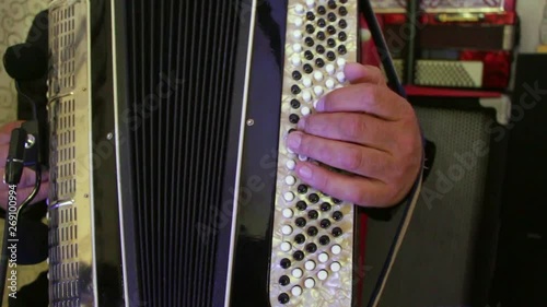 A man plays the accordion, pressing the keys with his fingers