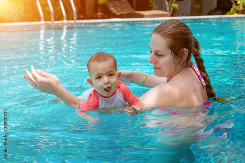 Happy little child with mother, Baby first time in a large pool and very impressed. Infant very happy, with open mouth, Teaching to swim