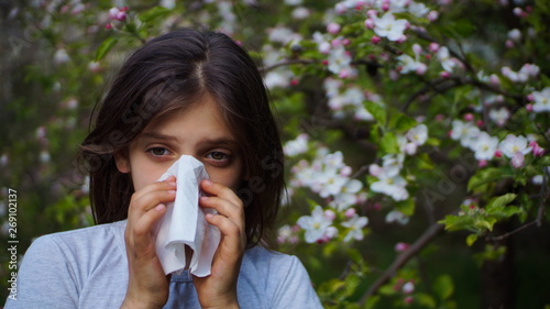 beautiful attractive little girl wipes her nose in a handkerchief because of spring allergy