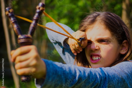 beautiful girl playing hunter with slingshot in nature