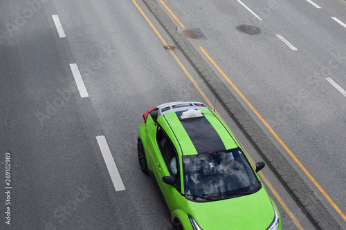 A passenger car of a green neon color is moving on the highway.