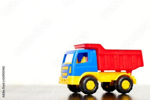 Children's toy truck, a multi-colored plastic dump truck on a white background, copy space. toys for boys.