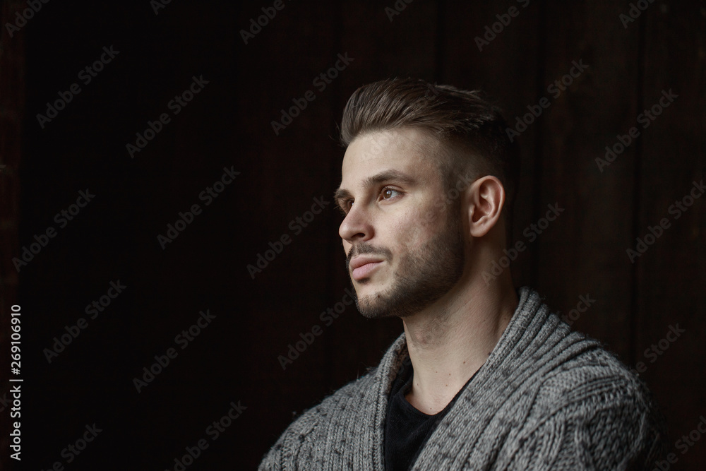 Muscular model young man with beard in knitted sweater on dark background. Fashion portrait of brutal sporty sexy strong muscle guy with modern trendy hairstyle. Model, fashion concept. Muscular model young man with beard in knitted sweater on dark background. Fashion portrait of brutal sporty sexy strong muscle guy with modern trendy hairstyle. Model, fashion concept.