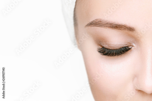 Eyelash extension procedure. Beautiful woman with long eyelashes and perfect glow clean skin. Girl in beauty salon getting facial treatment. Perfect trendy eyebrows.