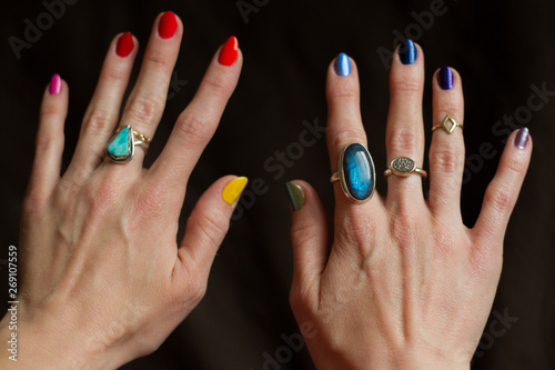 Hands with rings and rainbow colored fingernail polish