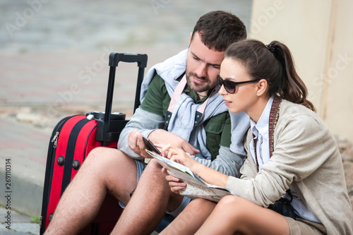 Happy Romantic Caucasian Couple Having a Trip Around the Town. Sitting on Floor and Examining the Map Together.