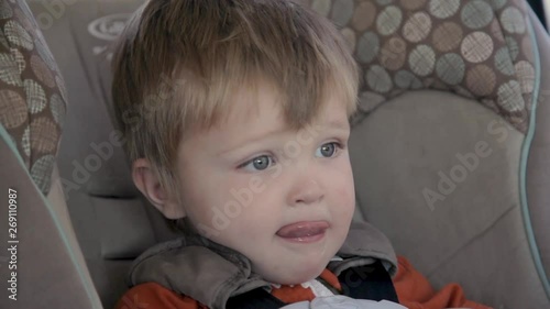 Child Sits in Car Seat and Looks Around