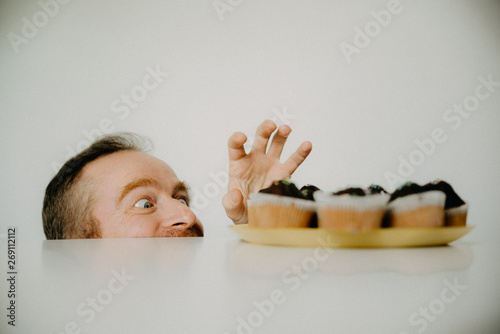 Fotografie A man on a diet watch cupcakes