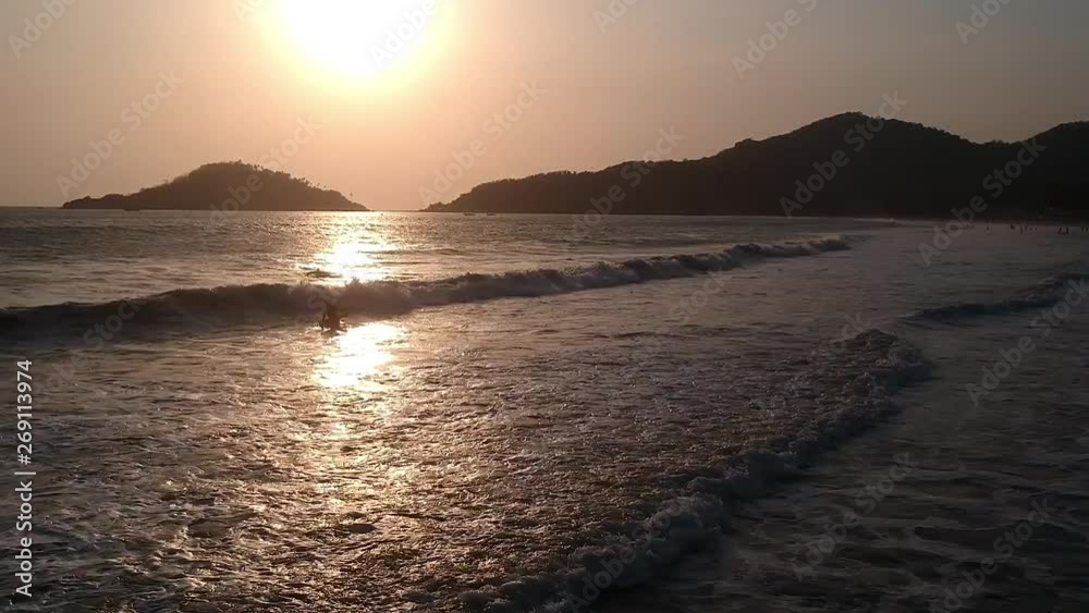 Flying forwards across rolling waves on Palolem Beach with silhouetted hills in the distance in Goa Flying forwards across rolling waves on Palolem Beach with silhouetted hills in the distance in Goa