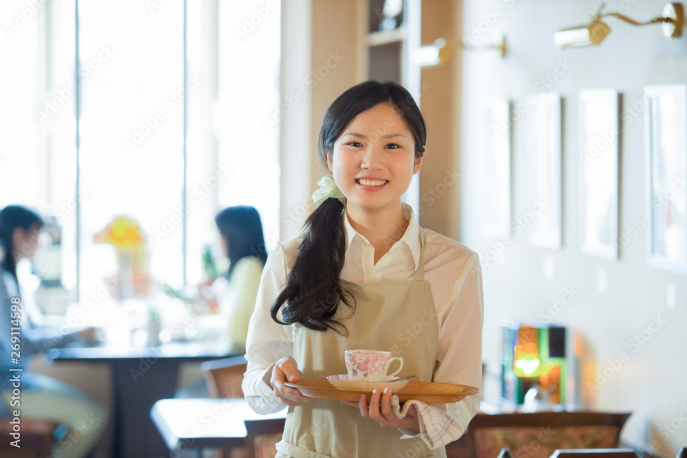 お盆を持ち微笑むカフェの店員 お盆を持ち微笑むカフェの店員